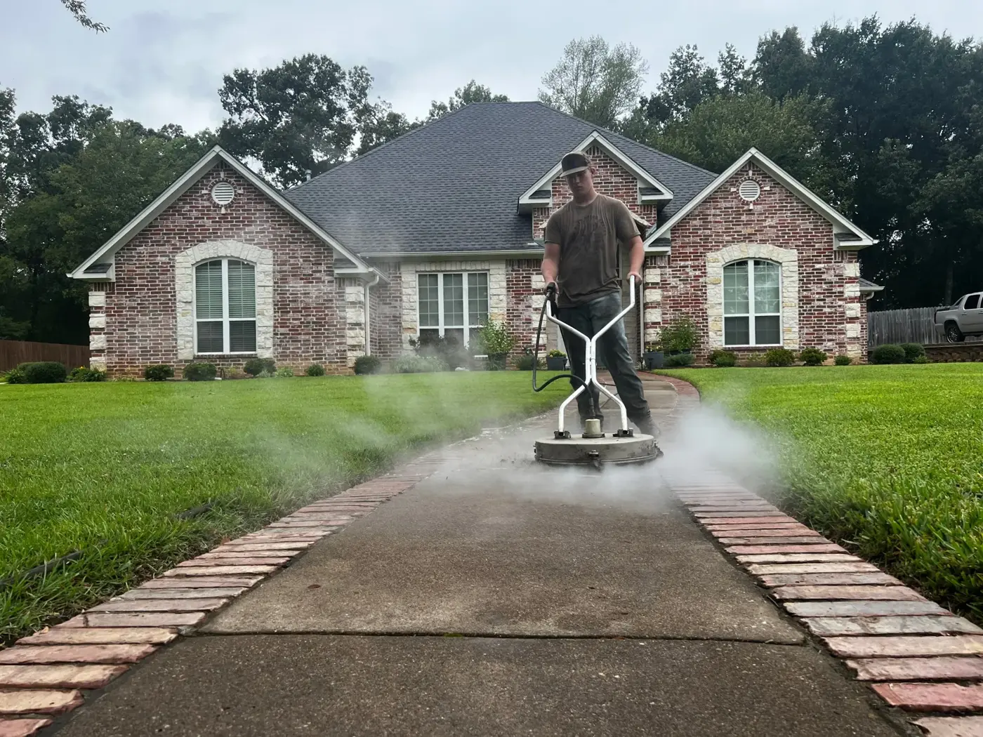 B&H technician running a surface cleaner on a brick-edged walkway